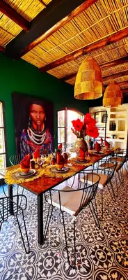 a dining room with a table with chairs and a painting at dar d'art Marrakech in Sraïri
