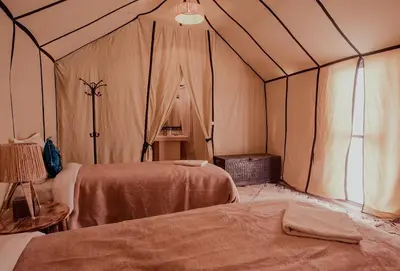 a room with two beds in a tent at Sandrock Luxury Camp in Merzouga