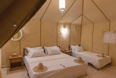 a bedroom with two beds in a tent at Sandrock Luxury Camp in Merzouga
