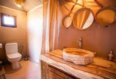 a bathroom with a wooden sink and mirrors on the wall at Sandrock Luxury Camp in Merzouga
