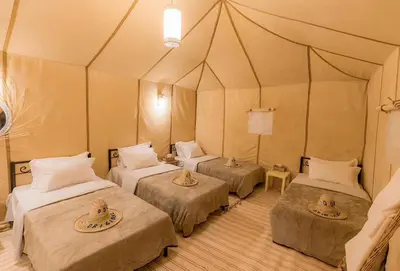 a room with three beds in a tent at Sandrock Luxury Camp in Merzouga