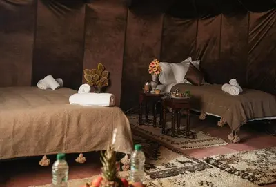a room with two beds and a table with towels at Sandrock Luxury Camp in Merzouga
