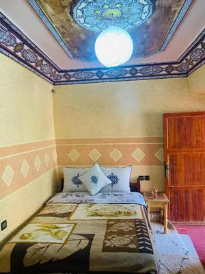 a bedroom with a bed with a painting on the ceiling at Hôtel Tawada in Azilal