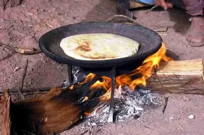 a pancake cooking in a pan over a fire at Hôtel Tawada in Azilal