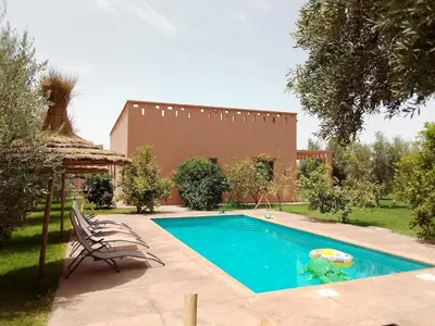 a swimming pool with two chairs and a house at Villa privative el marjaa in Ouled el guerne