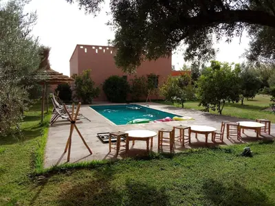 a pool with tables and chairs in a yard at Villa privative el marjaa in Ouled el guerne