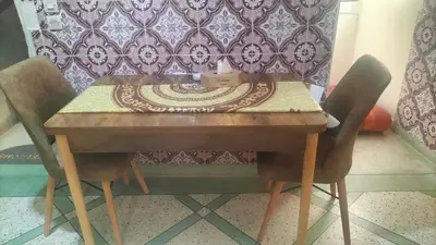 a wooden table with two chairs and a table with a clock on it at appartement bab boujloud in Fès