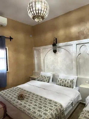 a bedroom with a large bed and a chandelier at Riad Azwaw in Er Rachidia