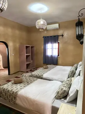 two large beds in a room with two chandeliers at Riad Azwaw in Er Rachidia