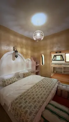 a bedroom with a large bed and a chandelier at Riad Azwaw in Er Rachidia