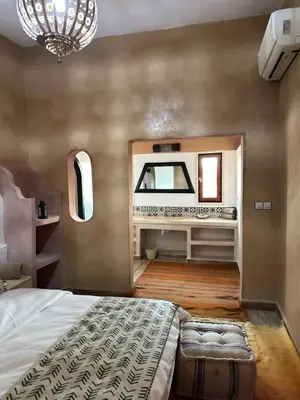a bedroom with a large bed and a mirror at Riad Azwaw in Er Rachidia