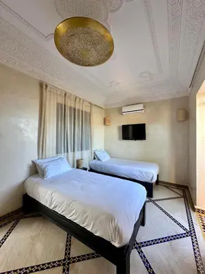 a hotel room with two beds and a chandelier at Villa Atika in El Bougaria