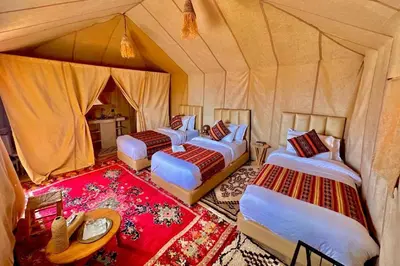 a bedroom with three beds in a tent at Merzouga Twilight Camp in Merzouga