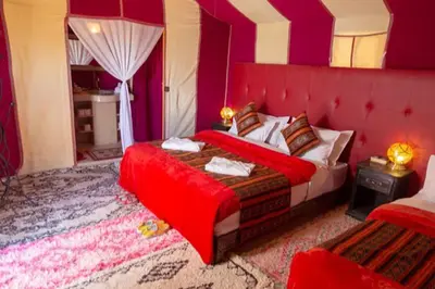 a bedroom with a bed with a red head board at Merzouga Twilight Camp in Merzouga