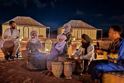a group of people sitting around a table in front of tents at Merzouga Twilight Camp in Merzouga