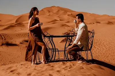 a man and a woman sitting at a table in the desert at Merzouga Twilight Camp in Merzouga