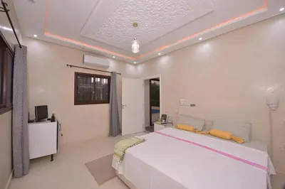 a bedroom with a white bed and a television at Villa Route de Fes in Marrakesh in Douar bel Rhanodour