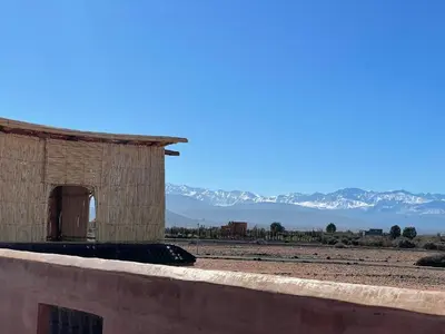 a small building on a wall with mountains in the background at AISHAMA Healing House in Aït Ourir