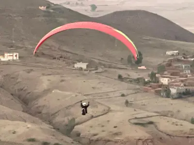 a paraglider is flying in the air over a mountain at AISHAMA Healing House in Aït Ourir
