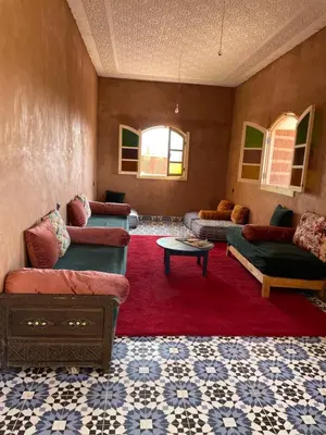 a living room with couches and a red rug at AISHAMA Healing House in Aït Ourir