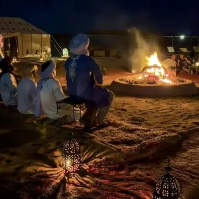 a group of people sitting around a fire pit at Luxury tent nomads in Merzouga
