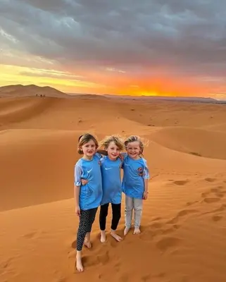 two little girls standing in the sand in the desert at Luxury tent nomads in Merzouga