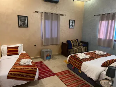 a bedroom with two beds and a couch at Hotel Berber Palace Merzouga in Merzouga