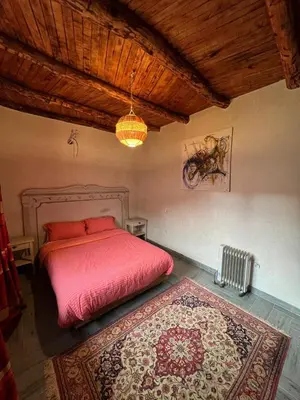 a bedroom with a red bed and a rug at Dar louqman ourika in Asguine