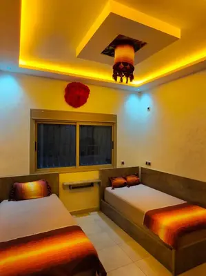 two beds in a room with yellow lighting at LH APPART 2 Très bel appartement avec vue sur les montagnes in Afourer