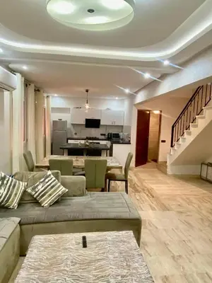 a living room with a couch and a kitchen at Rare, duplex 3 chambres, proche du centre in Oulad Akkou