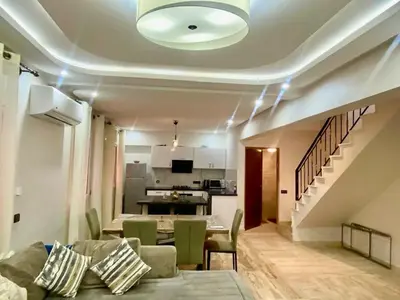a living room with a couch and a kitchen at Rare, duplex 3 chambres, proche du centre in Oulad Akkou