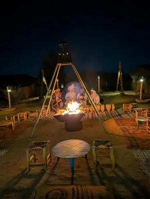 a group of people around a fire pit at night at Lunanir lodge Camp in Hassilabied