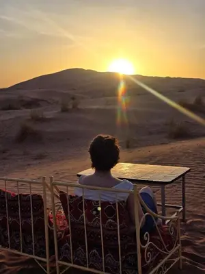 a person sitting in a chair watching the sunset at Lunanir lodge Camp in Hassilabied