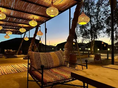 a porch swing with chandeliers and lights and a table at Lunanir lodge Camp in Hassilabied