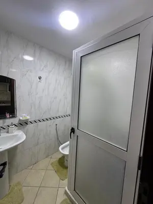 a bathroom with a toilet and a glass door at Studio Appart hotel in Oulad Akkou