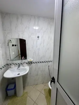 a white bathroom with a sink and a mirror at Studio Appart hotel in Oulad Akkou