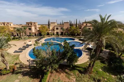 an aerial view of a resort with two pools and palm trees at Malaya Majestic in Srarhna