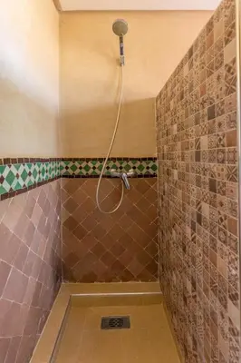a shower with a hose attached to a tiled wall at Malaya Majestic in Srarhna