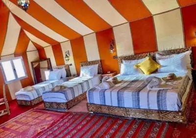 a bedroom with three beds in a room with a striped wall at Camp Lovers Desert in Merzouga