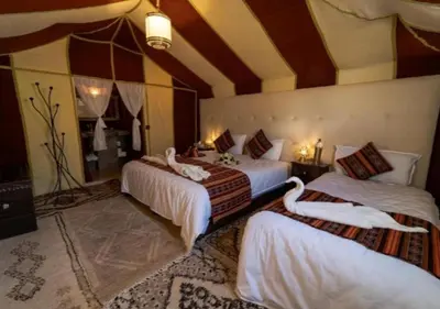 a bedroom with two beds with swans on them at Camp Lovers Desert in Merzouga