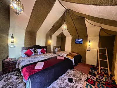 a bedroom with two beds in a room with aamed ceilings at Camp Lovers Desert in Merzouga