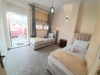 a bedroom with two beds and a balcony at City Center Apartment Fez in Fès