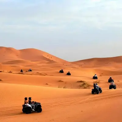 a group of people riding on atvs in the desert at Merzouga whisper camp in Merzouga