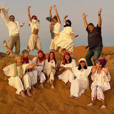 a group of people jumping in the sand at Merzouga whisper camp in Merzouga