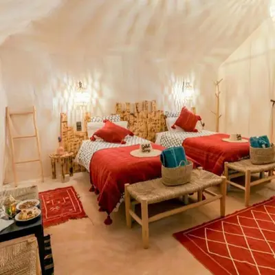 two beds in a room with red sheets at Merzouga whisper camp in Merzouga