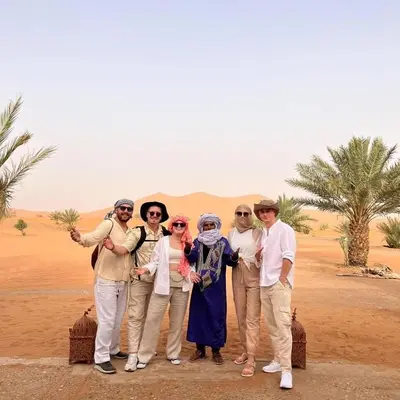a group of people posing for a picture in the desert at Merzouga whisper camp in Merzouga