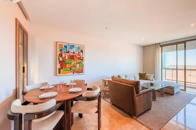 a dining room with a table and a couch at Azur Apartment pool & design in Oulad Akkou