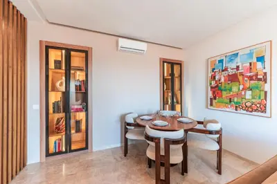 a dining room with a table and chairs and a painting at Azur Apartment pool & design in Oulad Akkou