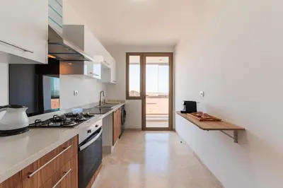 a kitchen with white counters and a stove top oven at Azur Apartment pool & design in Oulad Akkou