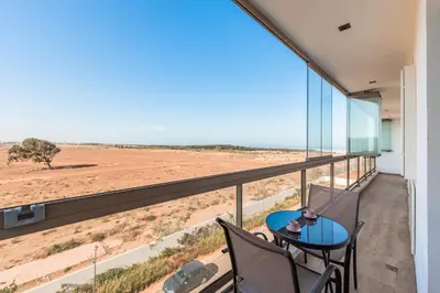 a balcony with a table and chairs and a view of the desert at Azur Apartment pool & design in Oulad Akkou